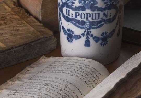 Apothecary Jar With Several Closed And One Open Handwritten Recipe Books (1)
