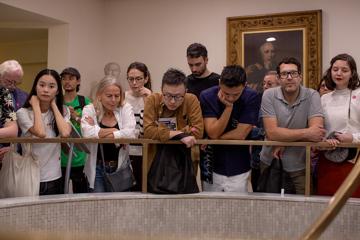 A tour group leans over a brass banister in the RCP