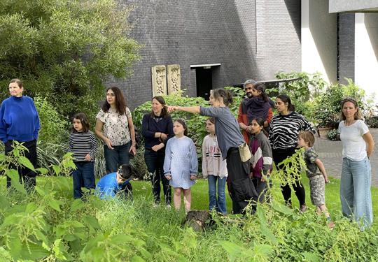 A group of families being shown the garden by a gardener